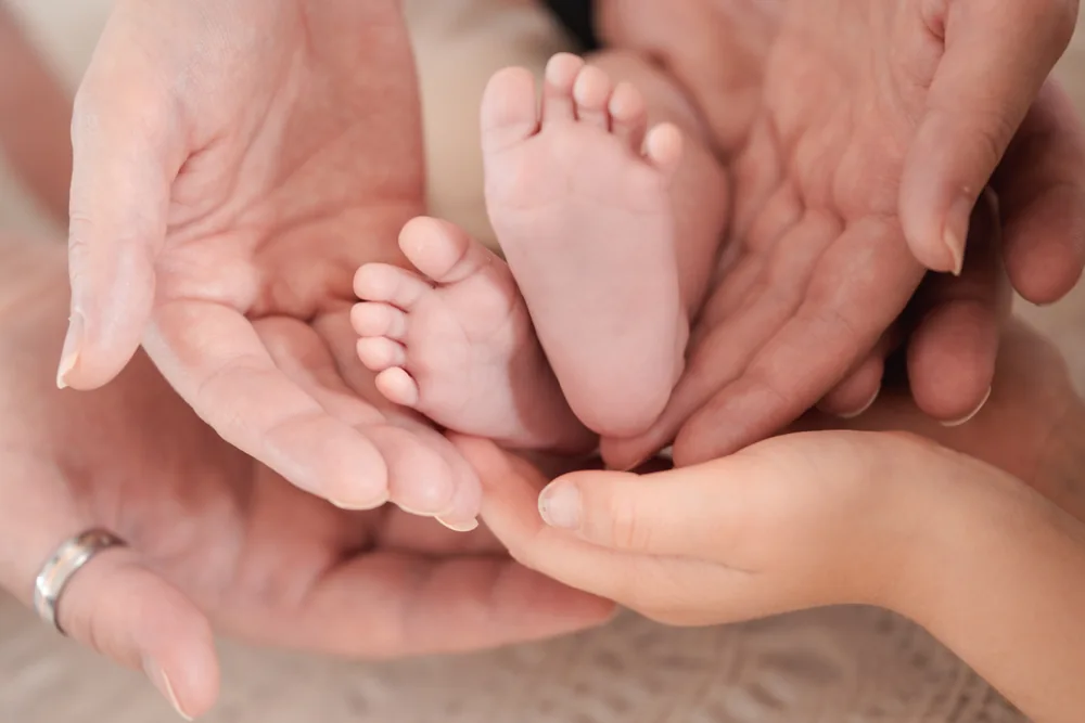 Kleine Babyfüße in den Händen der Eltern.
